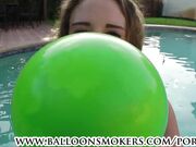 Busty teen blows to pop balloons outside in pool